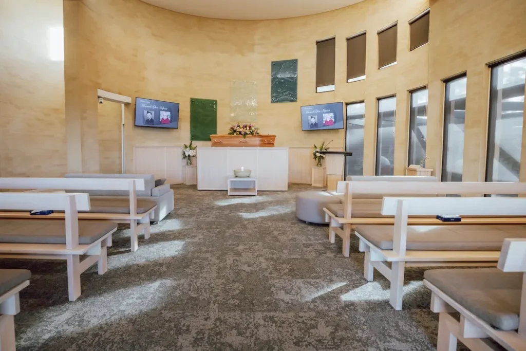 Full interior perspective down the centre aisle showing the circular sanctuary, cushioned pews, dual tribute screens, and catafalque at 42/110 Burvilles Rd, Mount Duneed.
