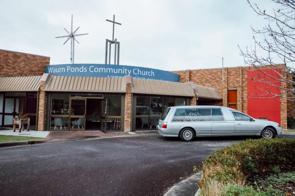 Exterior view of the main entrance and driveway at Waurn Ponds Community Chapel with a silver funeral hearse parked outside at 48 Waurnvale Dr, Belmont.