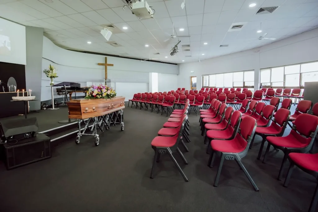 Semi-circular red seating arrangement facing the main stage inside Waurn Ponds Community Chapel, coordinated by Jonathan Hepner Funerals.